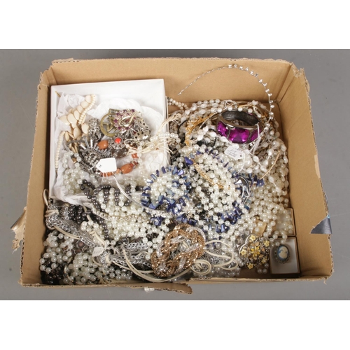 176 - A box of costume jewellery. Includes beads, bangles, brooches, etc.