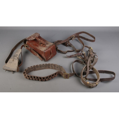 192 - A box of leather items. Includes cartridge belt, gun holsters, satchel, etc.