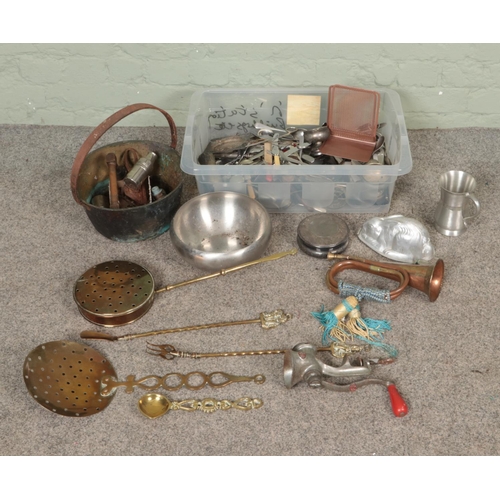 242 - A box of metalwares. Includes copper & brass bugle, jam pan, cutlery, casters, companion set, rabbit... 