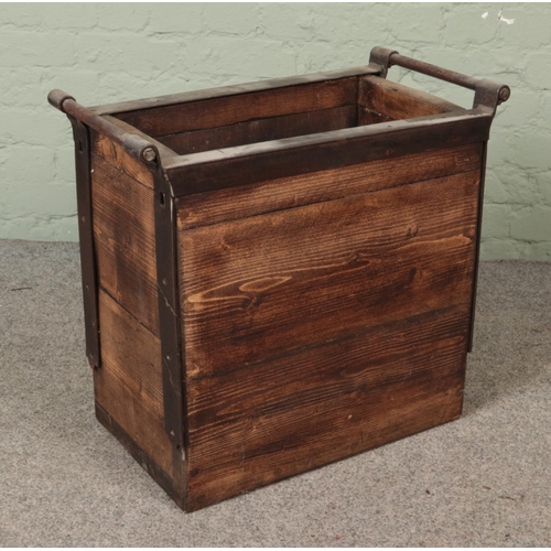 309 - A panelled log basket featuring metal surround and handles. Approx. dimensions 62cm x 58cm x 34cm.