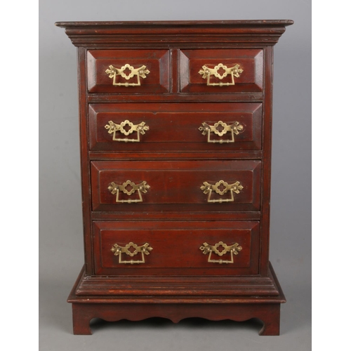 313 - A miniature chest of drawers with brass handles.

Hx56cm
Wx40cm
Dx20cm