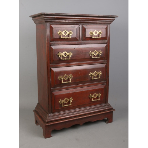 313 - A miniature chest of drawers with brass handles.

Hx56cm
Wx40cm
Dx20cm