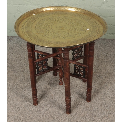 340 - An Eastern brass top table with decorative turned wooden base.