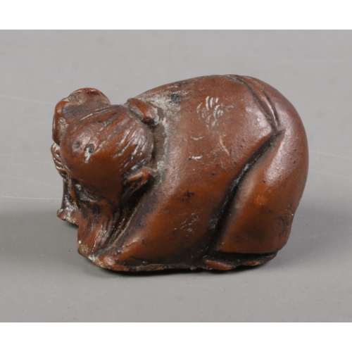 402 - A Japanese carved hardwood netsuke formed as crouching elder holding a staff.