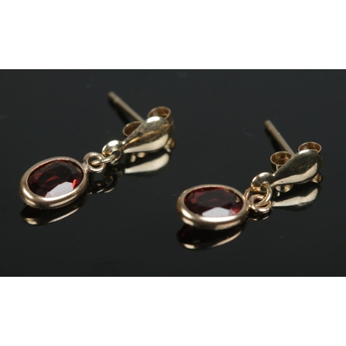 447 - A pair of small 9ct gold drop earrings set with garnets. Total weight 0.6g.