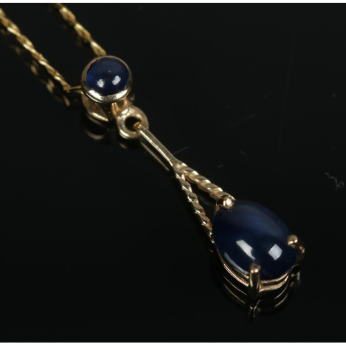 449 - A 9ct gold and sapphire pendant on chain set with two cabochon stones. Total weight 2.1g.