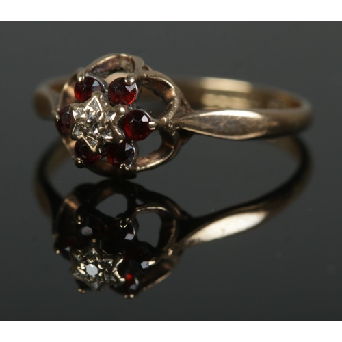 458 - A 9ct gold cluster ring set with six garnets surrounding a central diamond. Size Q, 1.8g.