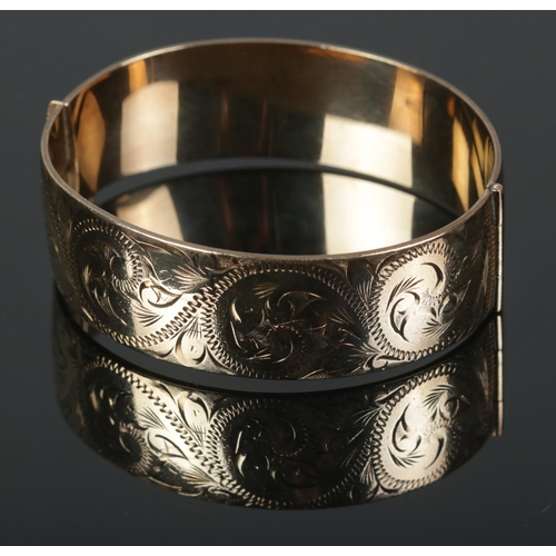 471 - A 9ct rolled gold bangle featuring engraved decoration to one half. Makers mark 'W.P' to inside.