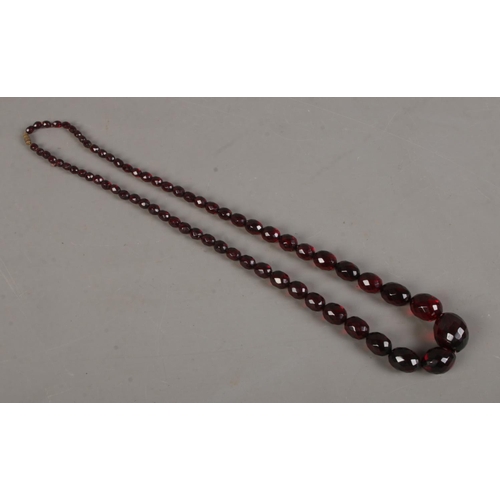 474 - A string of cherry red bakelite beads, graduated and faceted. Approx. length when clasped 39cm, 63.3... 