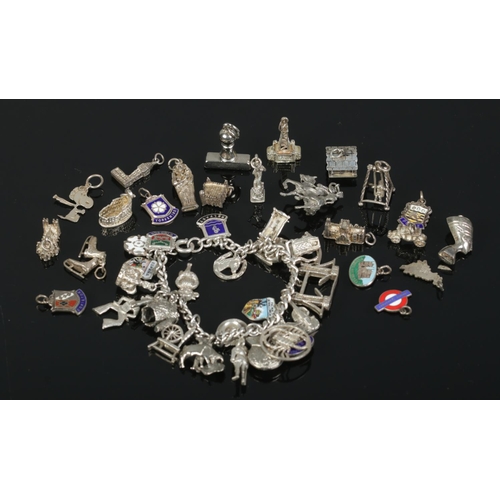 483 - A silver charm bracelet containing a large collection of Sterling Silver, Continental Silver and whi... 