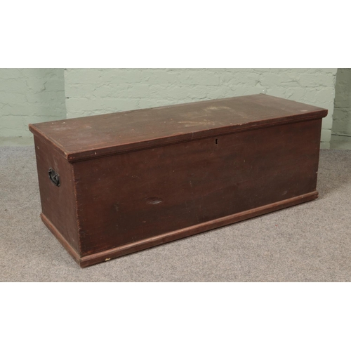 533 - An early 20th century stained pine blanket box of long proportions with twin handles and interior ca... 