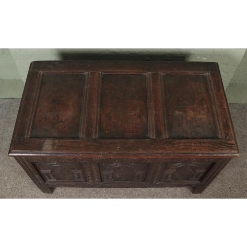 535 - An 18th century oak joined coffer with hinged top and profusely carved tri panel base fitted with in... 