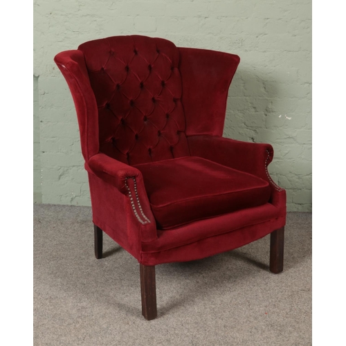 537 - A wing back arm chair with button back and red velvet upholstery.