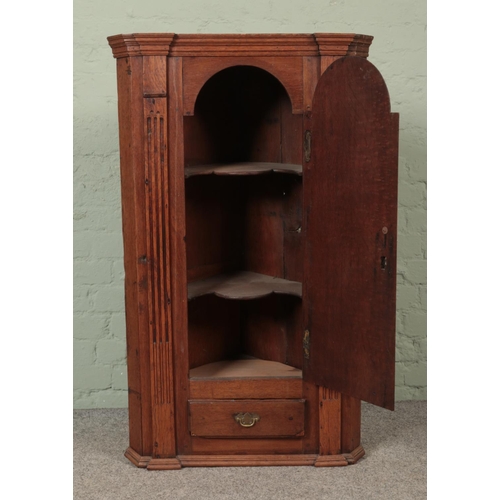 548 - An early Victorian oak hanging corner cupboard with  cupboard door over singular drawer flanked by f... 