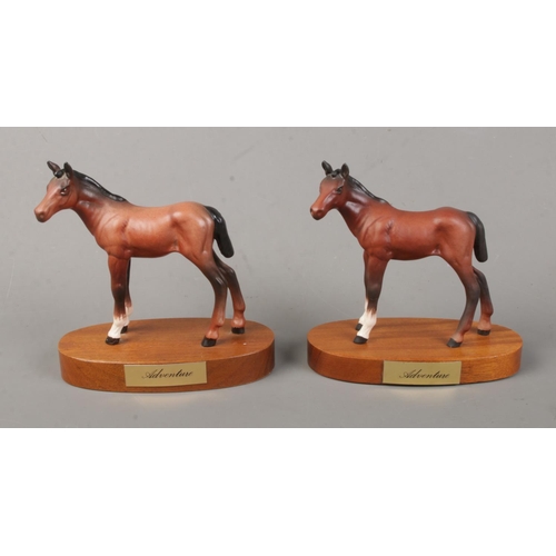 119 - Two ceramic horses on plinths titled 'Adventure': one Beswick and the other Royal Doulton.