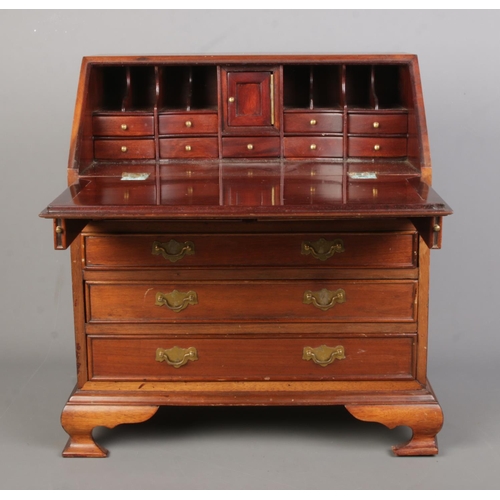 153 - A miniature mahogany bureau in the Georgian style with brass fittings. Height 46.5cm, Width 45cm, De... 