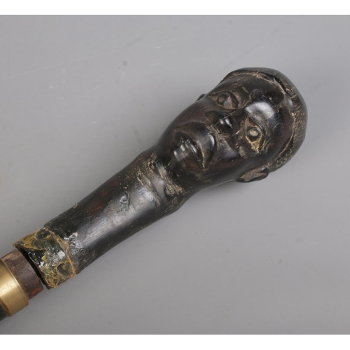 210 - An early 20th century African tribal sword stick with carved bust pommel. Length 94cm. CANNOT POST O... 