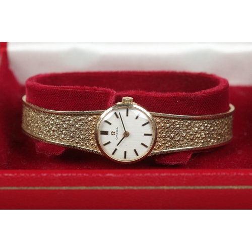 224 - A ladies 9ct gold Omega manual wristwatch on 9ct gold strap. Having satin dial and baton markers. In... 