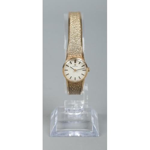 224 - A ladies 9ct gold Omega manual wristwatch on 9ct gold strap. Having satin dial and baton markers. In... 