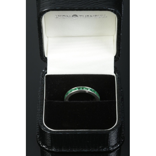 231 - A French platinum and emerald eternity ring, channel set with square cut stones. Stamped with 'Dog H... 