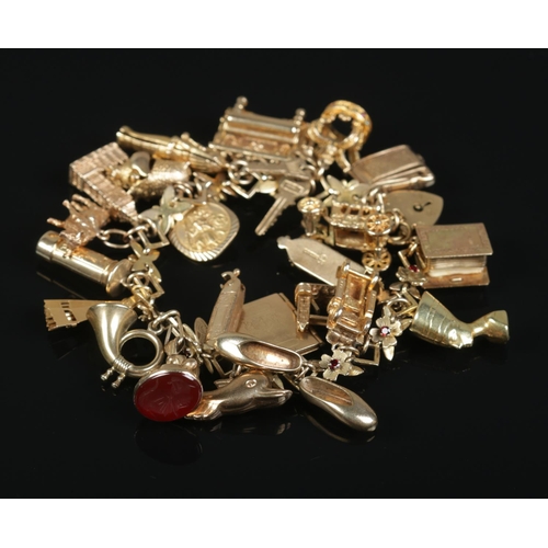 252 - A 9ct gold charm bracelet with floral and paste set links and contents of mostly 9ct gold charms. To... 