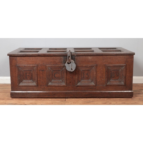 301 - An antique panelled oak coffer. Carved to the front with initials FC and dated 1589. Height 51cm, Wi... 