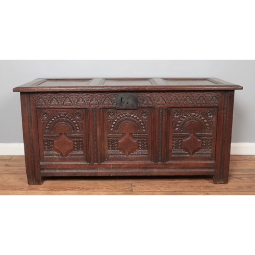 304 - An antique carved oak coffer. Height 62cm, Width 134cm, Depth 59cm.