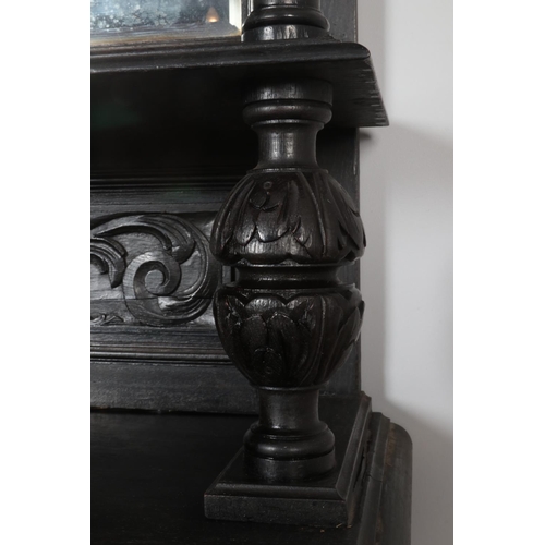 306 - An ebonised mirror back sideboard with floral and green man carved decoration.