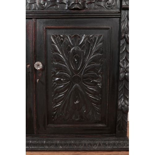 306 - An ebonised mirror back sideboard with floral and green man carved decoration.