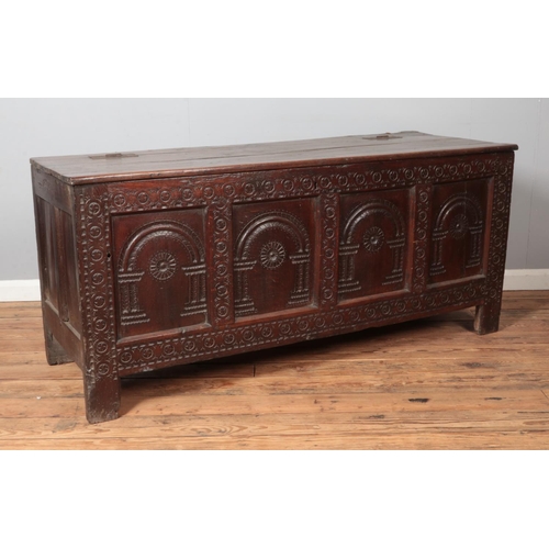 307 - A large antique carved and panelled oak coffer. Height 73cm, Width 163cm, Depth 59cm.