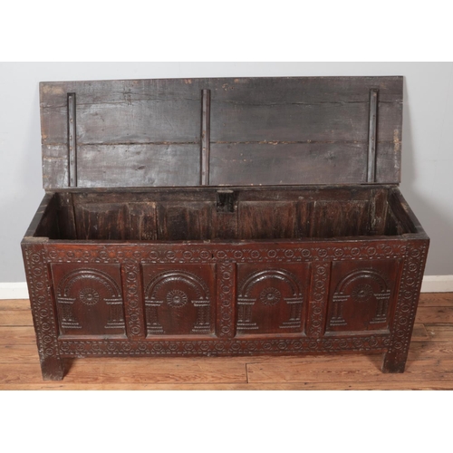 307 - A large antique carved and panelled oak coffer. Height 73cm, Width 163cm, Depth 59cm.