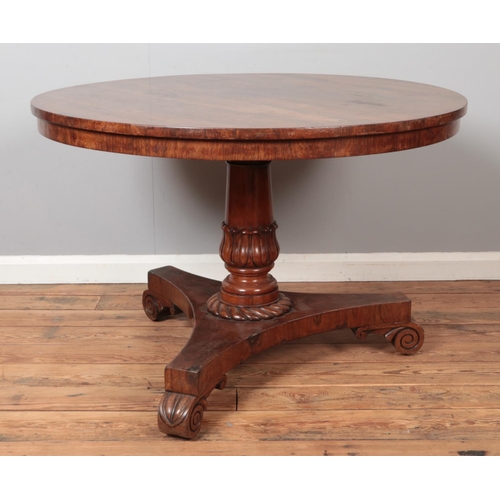 312 - A Victorian rosewood supper table with circular top and carved triform base. Diameter 107cm.