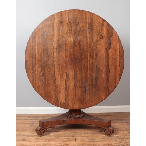 312 - A Victorian rosewood supper table with circular top and carved triform base. Diameter 107cm.