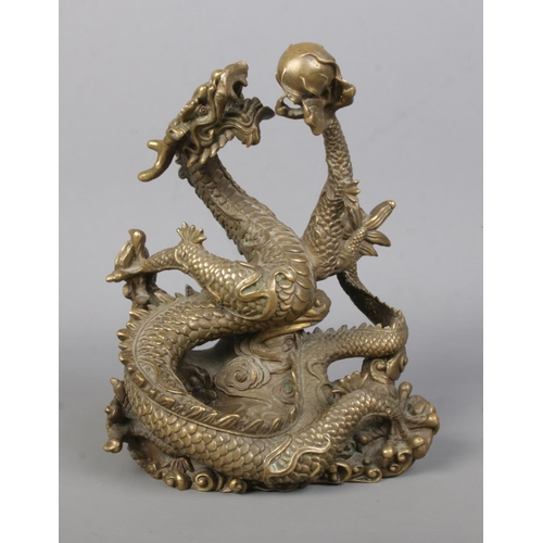 61 - A cast bronze sculpture of a Chinese dragon holding a flaming pearl. Height 18cm.