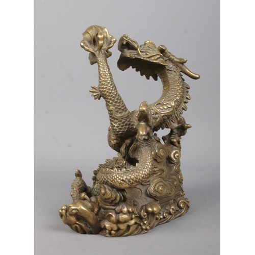 61 - A cast bronze sculpture of a Chinese dragon holding a flaming pearl. Height 18cm.