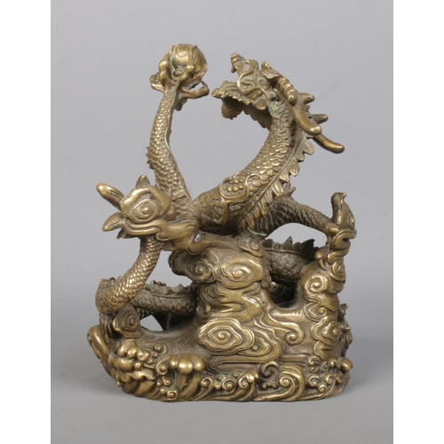 61 - A cast bronze sculpture of a Chinese dragon holding a flaming pearl. Height 18cm.