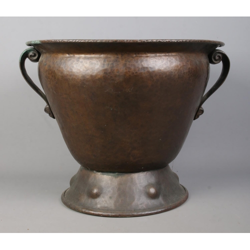 79 - An Arts & Crafts hammered copper twin handled vessel. Height 35.5cm.