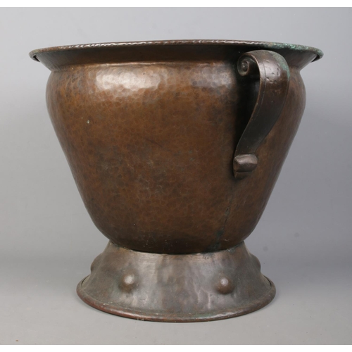 79 - An Arts & Crafts hammered copper twin handled vessel. Height 35.5cm.