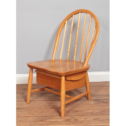 572 - An Ercol blonde elm child's chair featuring drawer to underside of seat.