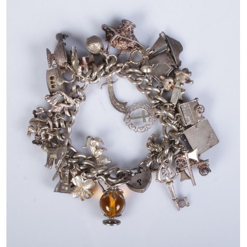 508 - A silver charm bracelet  featuring approx. 29 charms including seahorse, windmill, claret jug, key, ... 