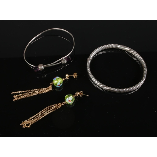 523 - Two silver bangles and a pair of silver gilt earrings, 25.6g