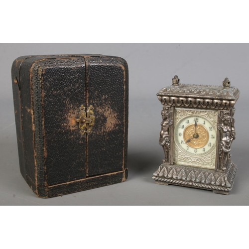 540 - An ornate metal miniature desk clock in fitted leather case. (9cm)