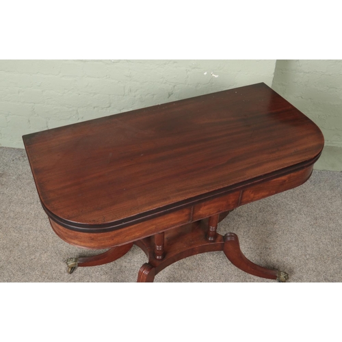 597 - A Victorian mahogany fold over table. Raised on brass lion paw castors.