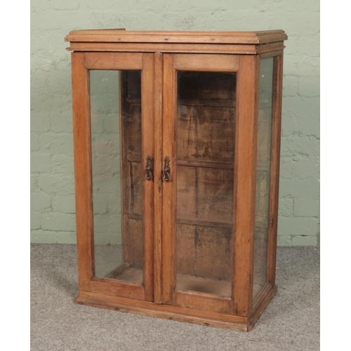 602 - A small stripped oak glazed cabinet. Height 94cm, Width 64cm, Depth 38cm.