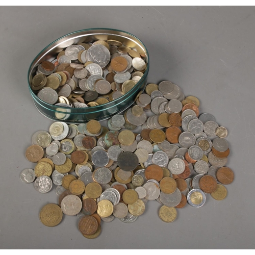 138 - A tin of world coins. Includes American, French, Cyprian, 1942 South Africa shilling, Portuguese etc... 