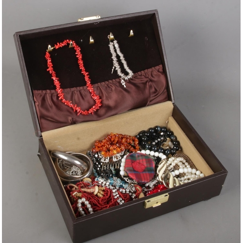 177 - A jewellery case with contents of costume jewellery. Includes amber/copal necklace, coral necklace, ... 