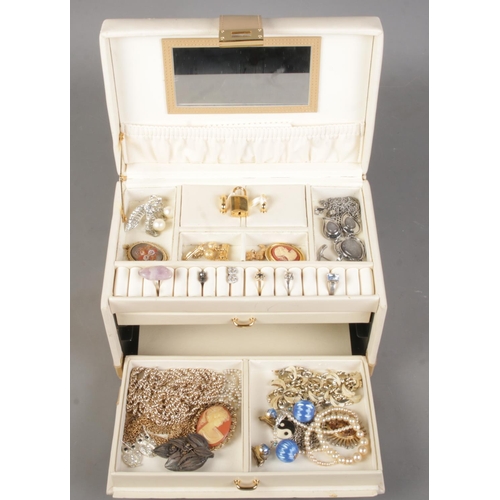 180 - A cream leather jewellery box with contents of costume jewellery. Includes rings, filigree brooch, s... 