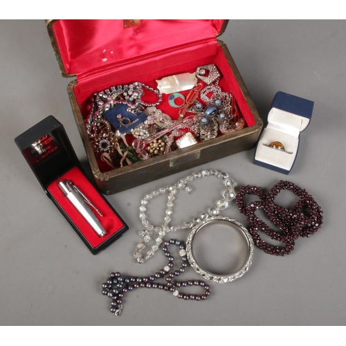 186 - A case of costume jewellery. Includes garnet necklace, pearl necklace, pipe lighter, enamelled ring ... 