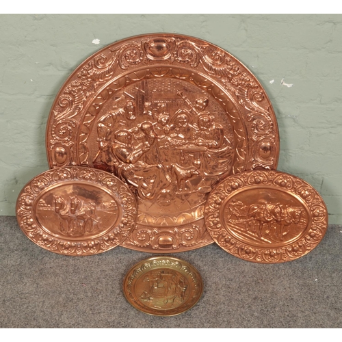 406 - A large embossed copper wall plate along with two smaller examples and a brass example. Largest 72cm... 