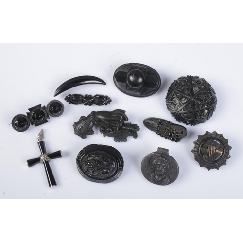 454 - Ten jet and similar brooches along with a white metal mounted crucifix pendant.